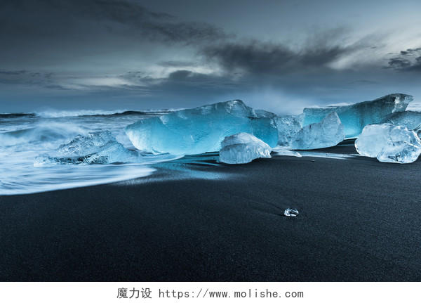 灰色天空下水晶冰山在南冰岛的黑色沙滩上